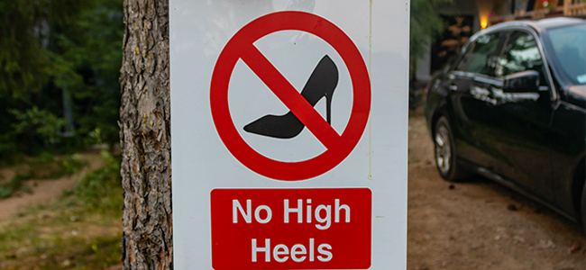A sign hung on a tree with the inscription No high heels